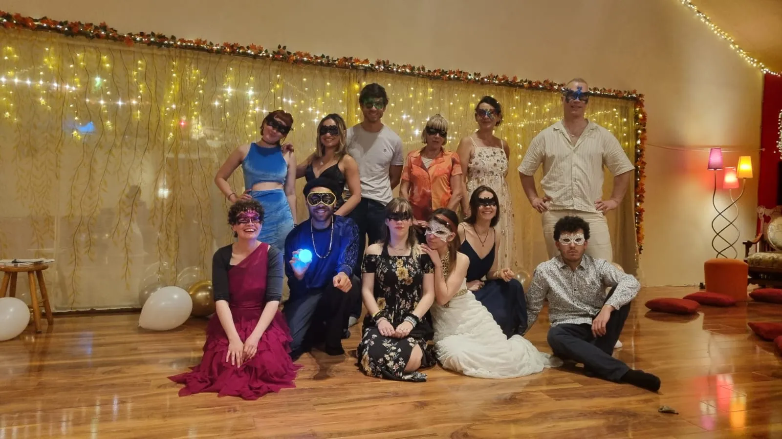 Photo de groupe du bal masqué dans la salle décorée.